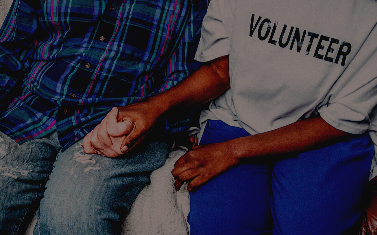 A Person Wearing Volunteer Shirt Holding a Persons Hand